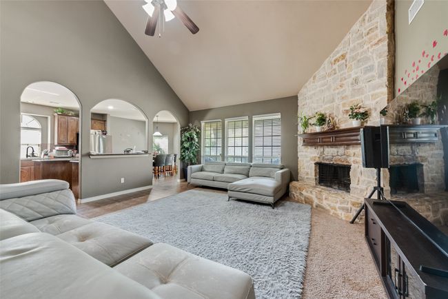 Living room featuring high vaulted ceiling, a fireplace, arched walkways, and ceiling fan | Image 7