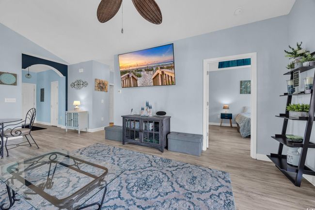 Living room featuring arched walkways, lofted ceiling, wood finished floors, and ceiling fan | Image 17