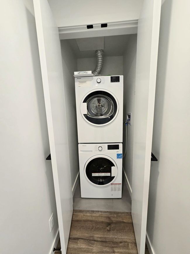 Laundry room with stacked washer / drying machine, wood finished floors, baseboards, and laundry area | Image 17