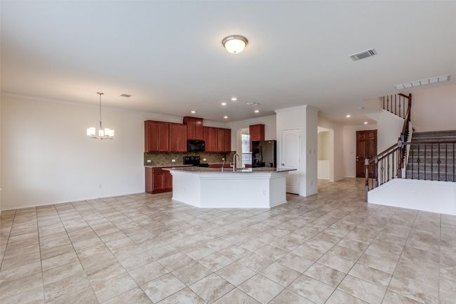 Kitchen featuring an inviting chandelier, visible vents, black appliances, open floor plan, and backsplash | Image 4