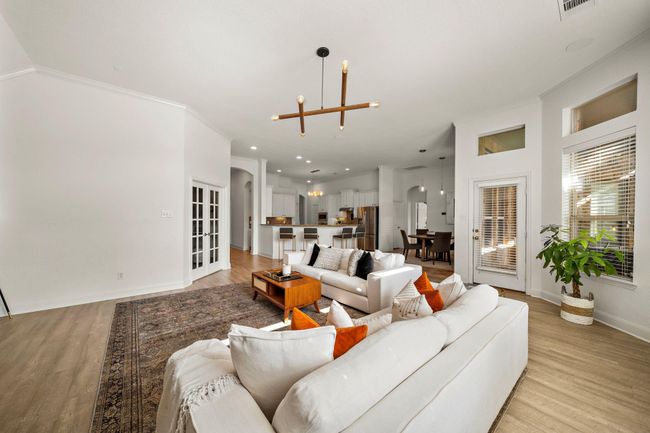 The expansive living room offers an ideal setting for gatherings, featuring abundant natural light, a cozy fireplace, and patio access for seamless indoor-outdoor living. With a modern open layout, ample seating space, and designer lighting, this area combines functionality with elegance. | Image 14