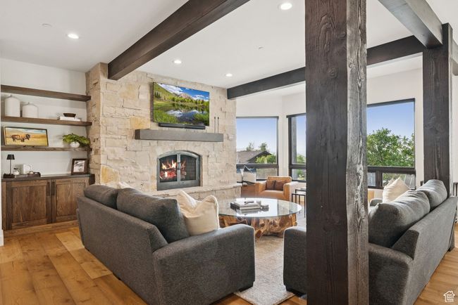 Living room with light wood-style floors, beam ceiling, a stone fireplace, and recessed lighting | Image 44