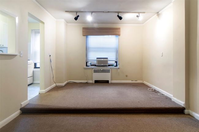 Carpeted spare room with rail lighting, crown molding, and radiator heating unit | Image 6