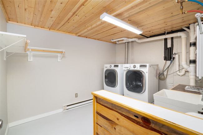 Laundry room featuring washing machine and dryer, baseboard heating, and wood ceiling | Image 29
