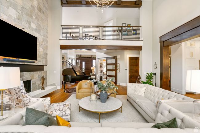 Living area with baseboards, a high ceiling, a fireplace, beam ceiling, and wood finished floors | Image 21