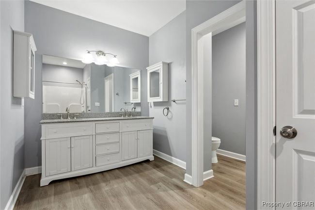 Full bath featuring baseboards, toilet, wood finished floors, a shower, and double vanity | Image 25