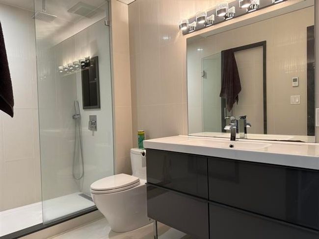 Bathroom featuring walk in shower, vanity, and tile walls | Image 6