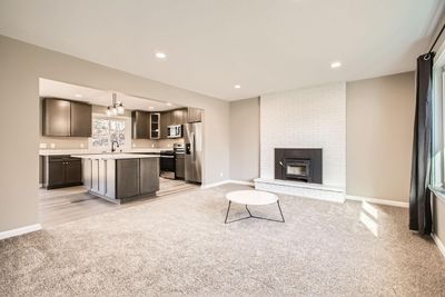 Spacious living room with a cozy wood burning fireplace surrounded by white brick | Image 3