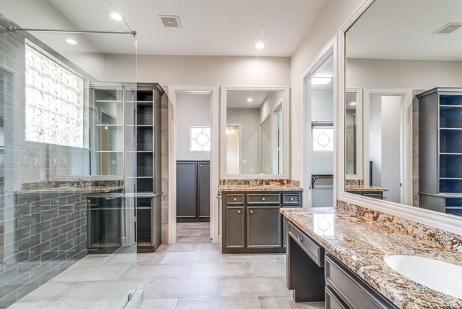 Primary en suite is updated with granite counter tops, two vanities, and gorgeous custom shower. | Image 8