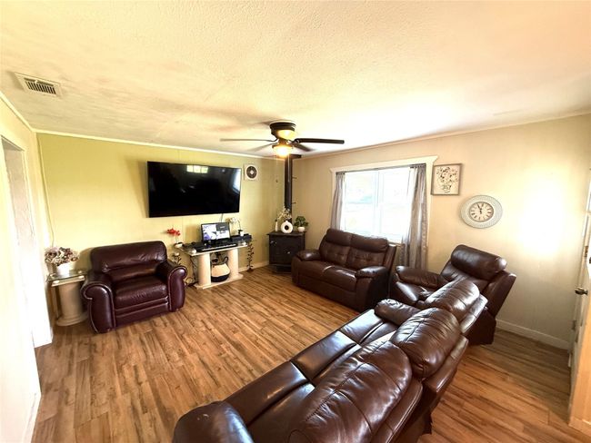Living area featuring wood finished floors, ceiling fan, ornamental molding, and a textured ceiling | Image 9