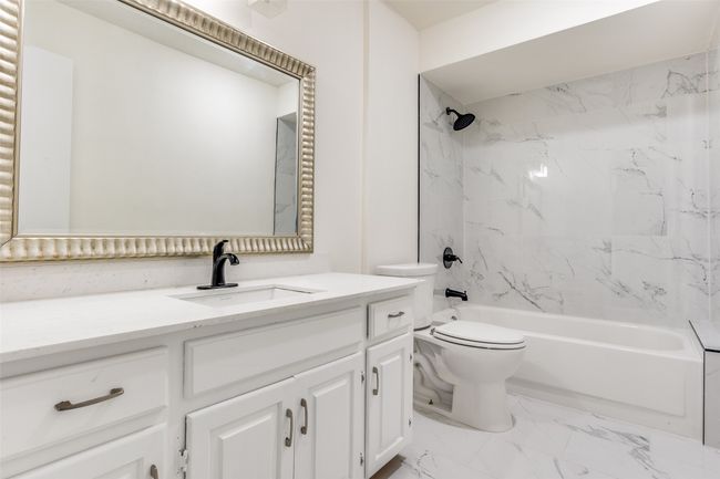 Bathroom with vanity, marble look tile flooring, shower combination, and toilet | Image 16