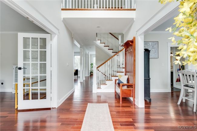 Entrance foyer featuring crown molding, baseboards, a towering ceiling, wood finished floors, and stairway | Image 4
