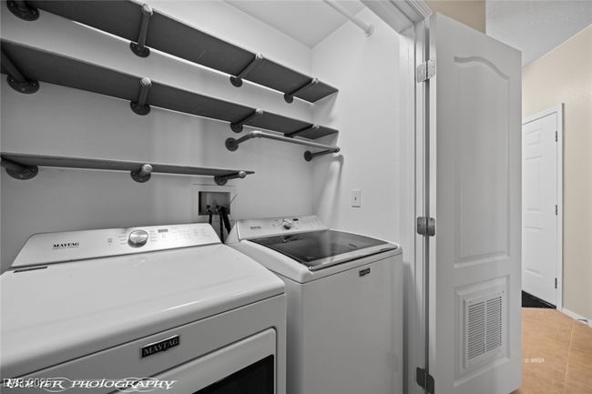 Clothes washing area with independent washer and dryer, light tile patterned floors, laundry area, and visible vents | Image 17
