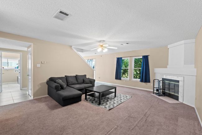Living room featuring carpet flooring, a ceiling fan, a textured ceiling, baseboards, and a premium fireplace | Image 8
