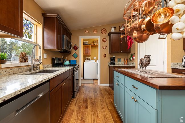 Kitchen featuring sink, wooden counters, vaulted ceiling, stainless steel appliances, and washing machine and dryer | Image 8