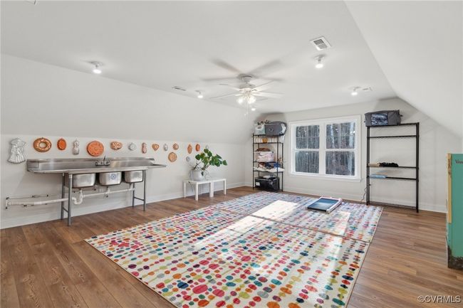 Rec room with visible vents, a ceiling fan, wood finished floors, baseboards, and vaulted ceiling | Image 41