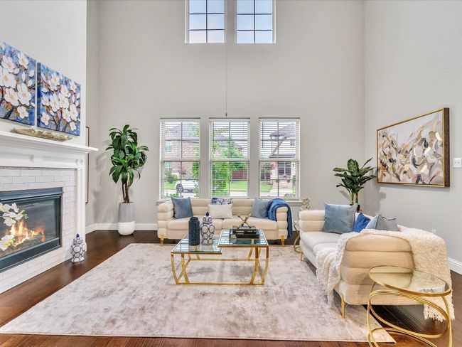 Living area featuring a towering ceiling, dark wood-style floors, and a fireplace | Image 4