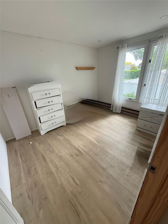 Unfurnished bedroom with light wood-style floors and baseboard heating | Image 5