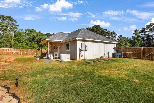 Rear view of house with board and batten siding, a fenced backyard, a shingled roof, and a lawn | Image 31