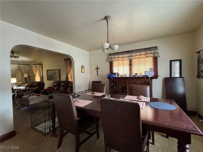 Carpeted dining space featuring an inviting chandelier, baseboards, and arched walkways | Image 5
