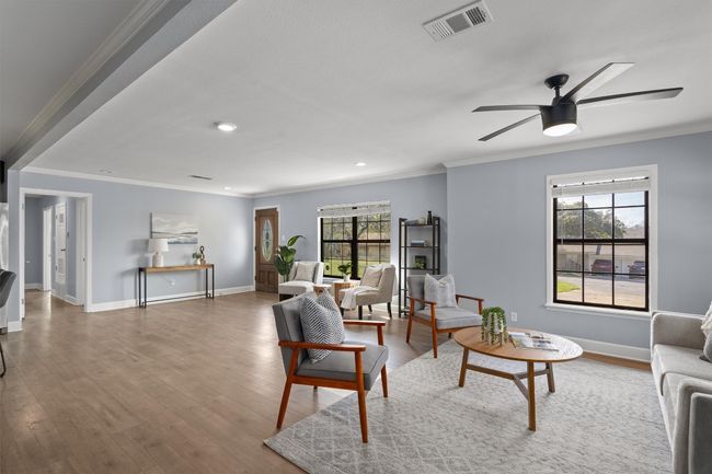 Living room with crown molding, wood finished floors, visible vents, and baseboards | Image 6