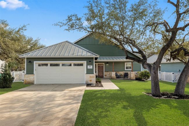 View of front of home with a standing seam roof, stone siding, driveway, an attached garage, and a metal roof | Image 36