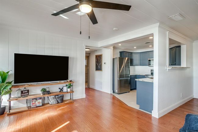 Living area with crown molding, ceiling fan, light wood-style floors, and baseboards | Image 12