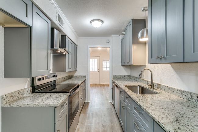 Kitchen featuring a sink, stainless steel appliances, light wood finished floors, wall chimney exhaust hood, and visible vents | Image 11