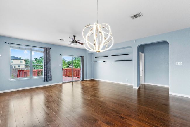 Unfurnished living room featuring arched walkways, dark wood-type flooring, a chandelier, and a ceiling fan | Image 10