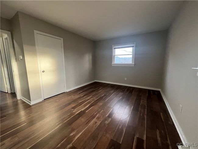 Unfurnished bedroom featuring baseboards and dark wood-style flooring | Image 6