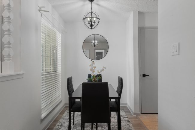 Dining space featuring light wood-style flooring, a textured ceiling, baseboards, and an inviting chandelier | Image 17