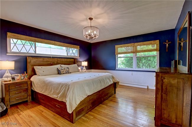Bedroom featuring a baseboard radiator, multiple windows, and light wood finished floors | Image 23