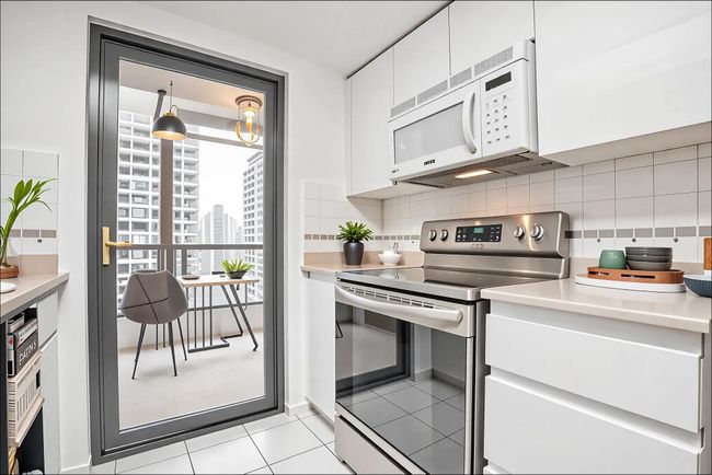 Kitchen featuring white microwave, white cabinetry, light countertops, stainless steel electric range, and backsplash | Image 8