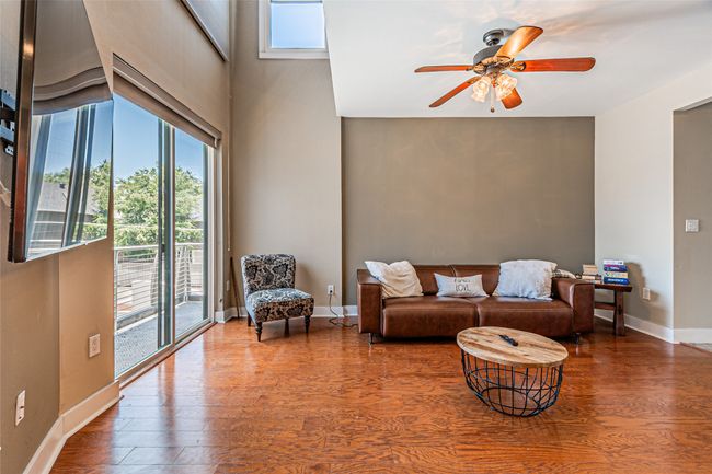 Living area featuring plenty of natural light, wood finished floors, and a ceiling fan | Image 5