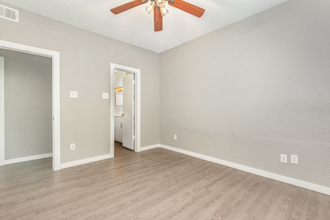 Unfurnished bedroom featuring wood finished floors, baseboards, ensuite bath, and a ceiling fan | Image 5