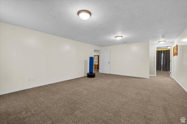 Empty room with a textured ceiling, carpet, and baseboards | Image 11
