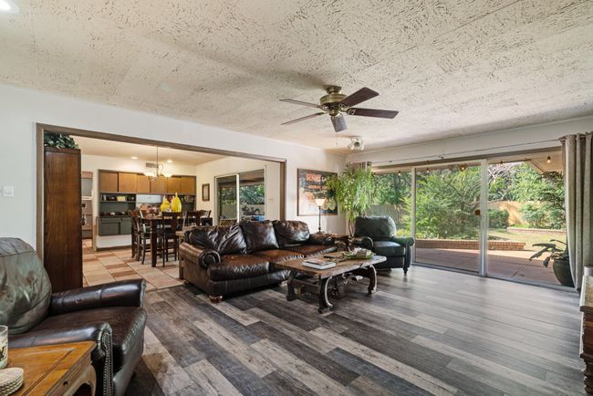 Living room featuring plenty of natural light, wood finished floors, ceiling fan, and a chandelier | Image 12