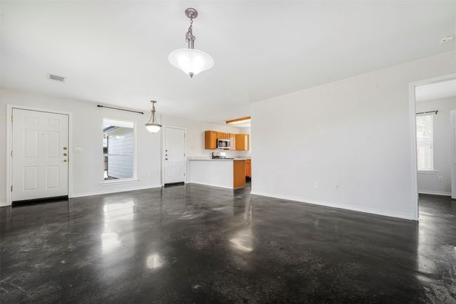 Unfurnished living room featuring finished concrete floors and baseboards | Image 6