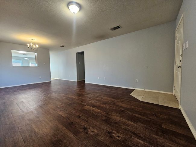 Empty room with a chandelier and dark wood-type flooring | Image 7