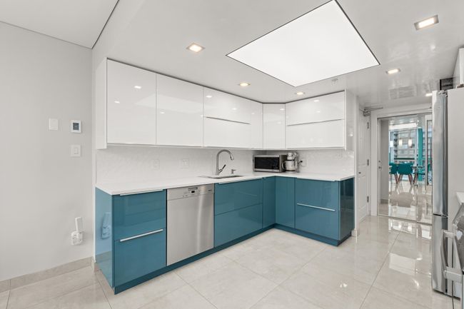 Kitchen with white cabinetry, stainless steel appliances, blue cabinets, a sink, and modern cabinets | Image 16