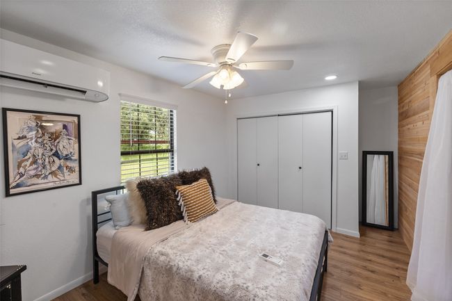 Bedroom with a closet, an AC wall unit, baseboards, and wood finished floors | Image 32