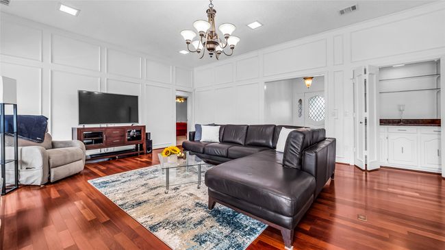 Living area with a decorative wall, a chandelier, and dark wood-style floors | Image 12