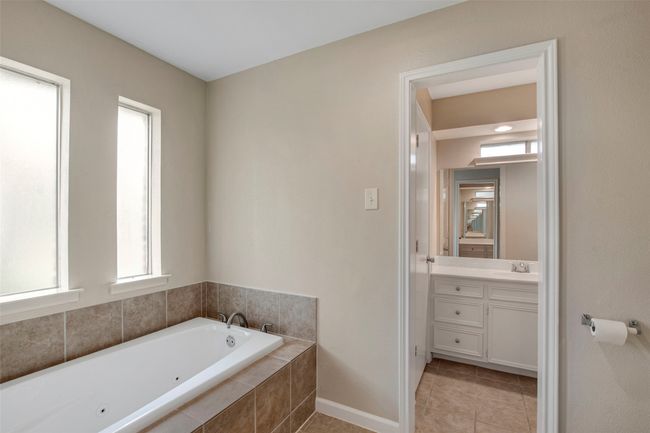 Full bathroom featuring vanity, tile patterned flooring, baseboards, and a tub with jets | Image 8
