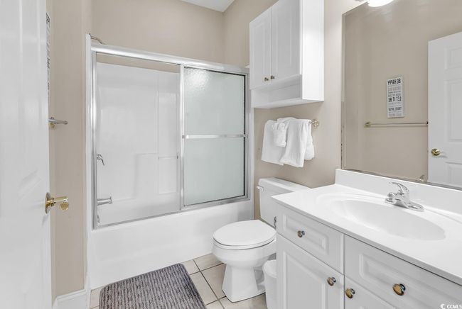 Bathroom with tile patterned floors, toilet, vanity, and shower / bath combination with glass door | Image 22