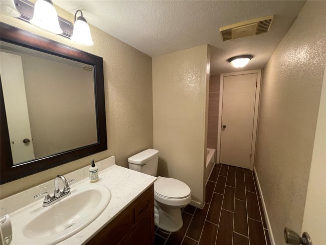 Bathroom with a textured wall, toilet, a textured ceiling, and vanity | Image 18