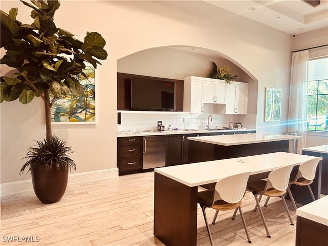 Community Amenities Kitchen featuring a kitchen island, dark brown cabinets, light hardwood / wood-style floors, and white cabinetry | Image 50