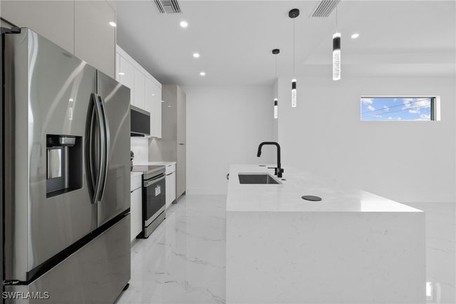 Kitchen featuring stainless steel appliances, a sink, modern cabinets, light marble finish floors, and recessed lighting | Image 8