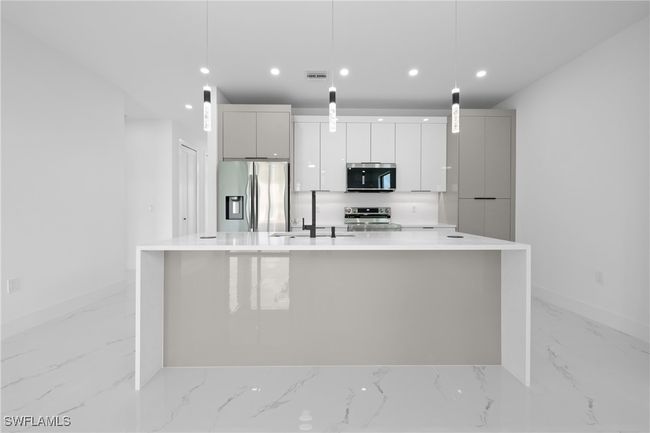 Kitchen featuring appliances with stainless steel finishes, light marble finish floors, baseboards, a spacious island, and recessed lighting | Image 7
