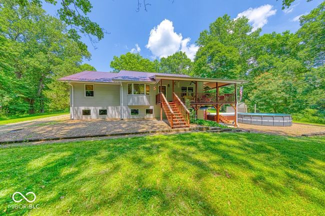 rear view of property with stairs, a yard, a metal roof, an outdoor pool, and a patio area | Image 60