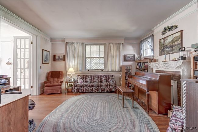 Living area with ornamental molding, a fireplace, and wood finished floors | Image 10
